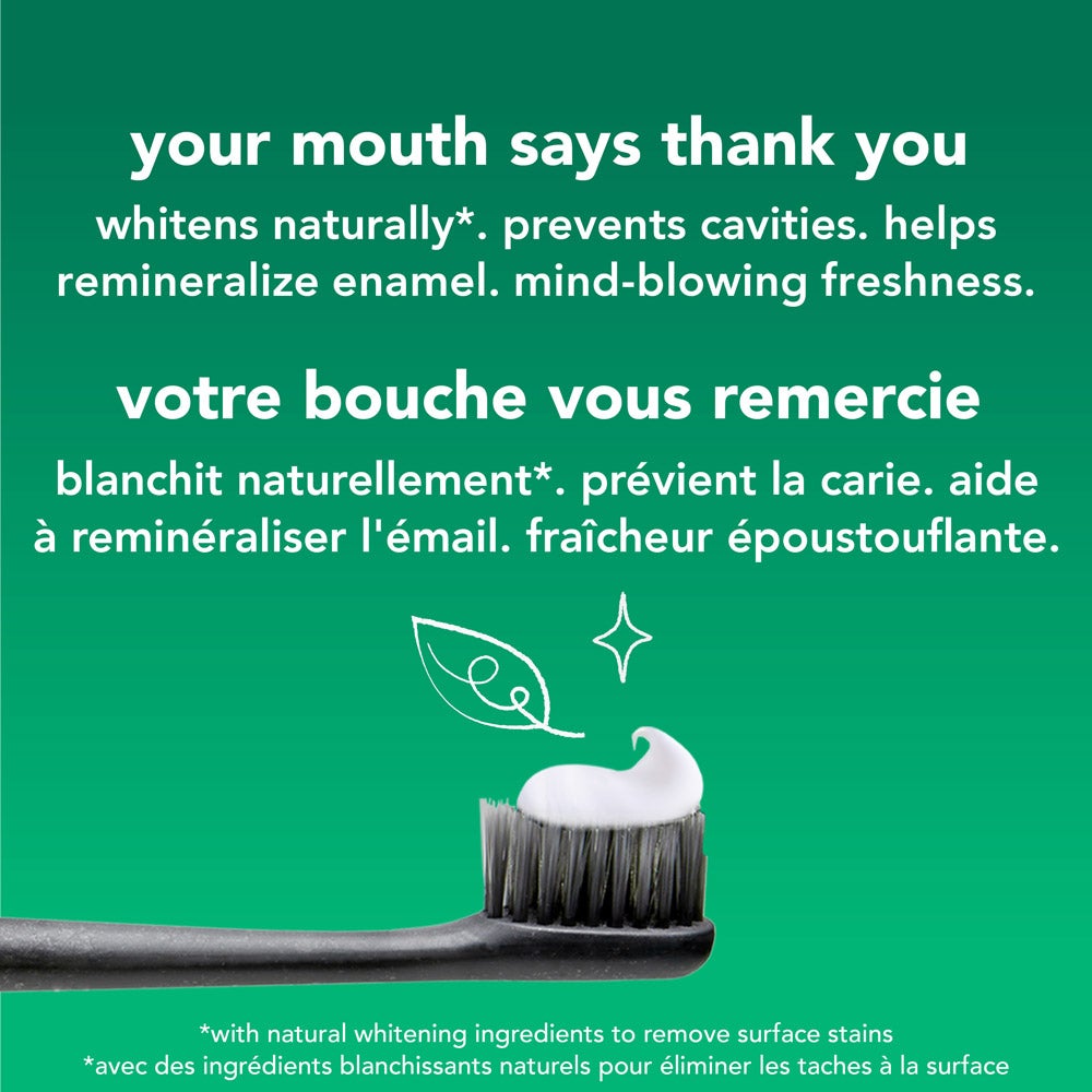 Gros plan sur une brosse à dents avec une noisette de dentifrice blanc, sur un fond vert. Au-dessus de la brosse à dents se trouve l'illustration d'une feuille blanche. Le texte énumère les avantages du dentifrice : « blanchit naturellement, prévient la carie, aide à reminéraliser l’émail, fraîcheur époustouflante » en anglais et en français.