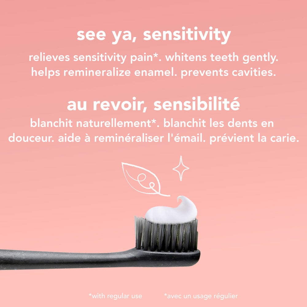 A close-up of a black toothbrush with a dollop of white  See Ya Sensitivity toothpaste is surrounded by fresh mint leaves and pieces of coconut on a pink background. Text highlights "natural mint flavor" and "with coconut oil" in both English and French. toothpaste on its bristles, set against a pink background. Text highlights product benefits: relieves sensitivity pain, whitens teeth gently, helps remineralize enamel, and prevents cavities, in both English and French.