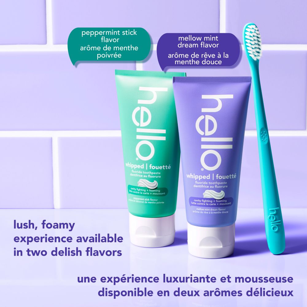 Deux tubes de dentifrice fouetté hello, un sarcelle (arôme de menthe poivrée) et un violet (arôme de rêve à la menthe douce), présentés à côté d'une brosse à dents sarcelle. Le texte se lit : Une expérience luxuriante et mousseuse disponible en deux arômes délicieux.