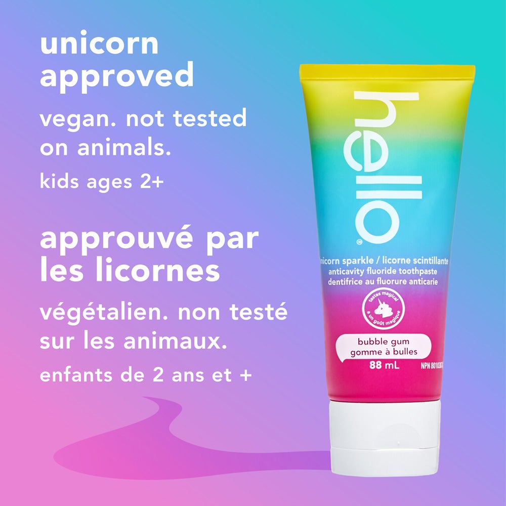 A tube of hello unicorn sparkle bubble gum fluoride toothpaste stands upright against a pastel rainbow background. The text next to it reads, "unicorn approved, vegan, not tested on animals, kids ages 2+."